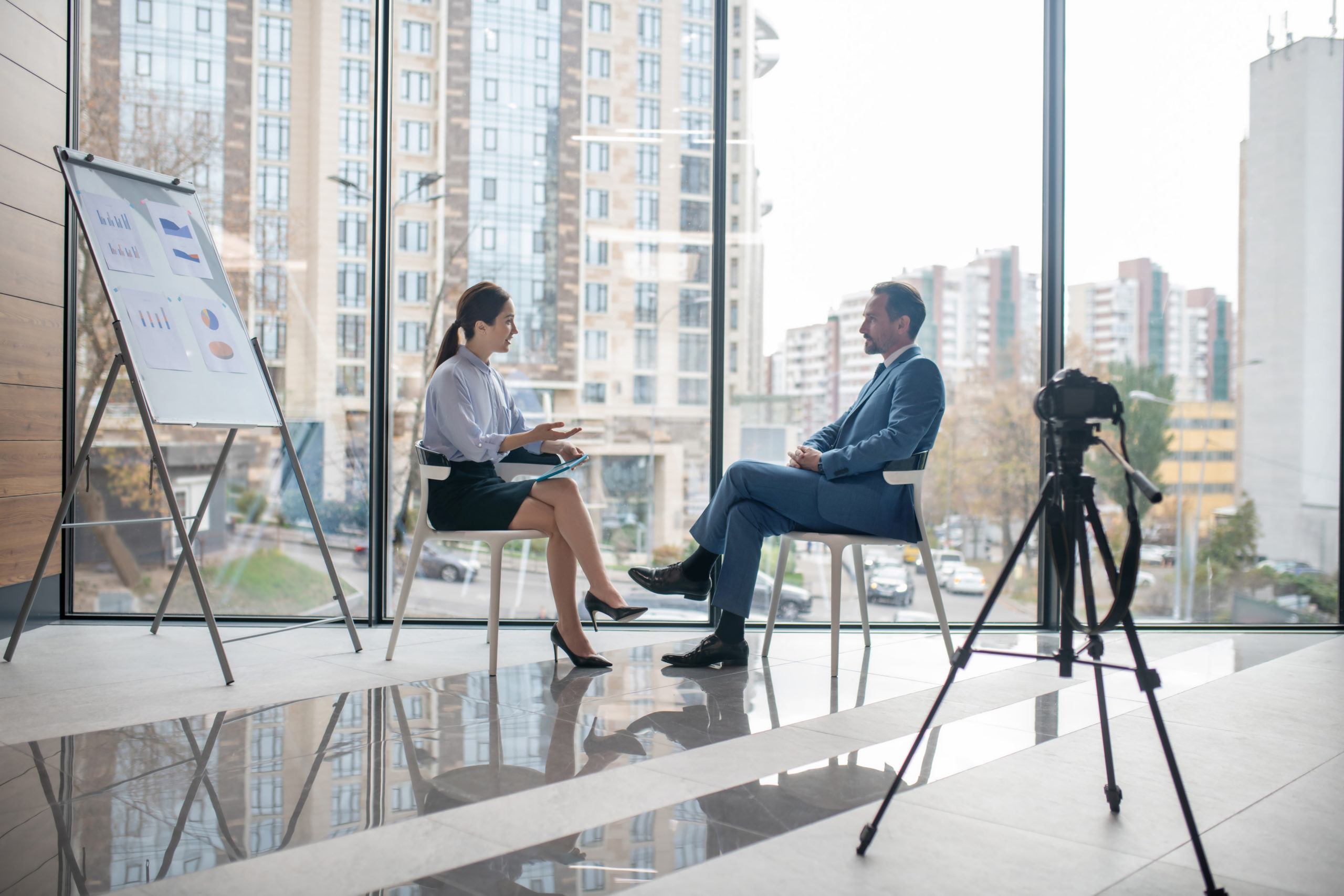 Giving the interview. Successful rich investor giving the interview to famous journalist sitting near window