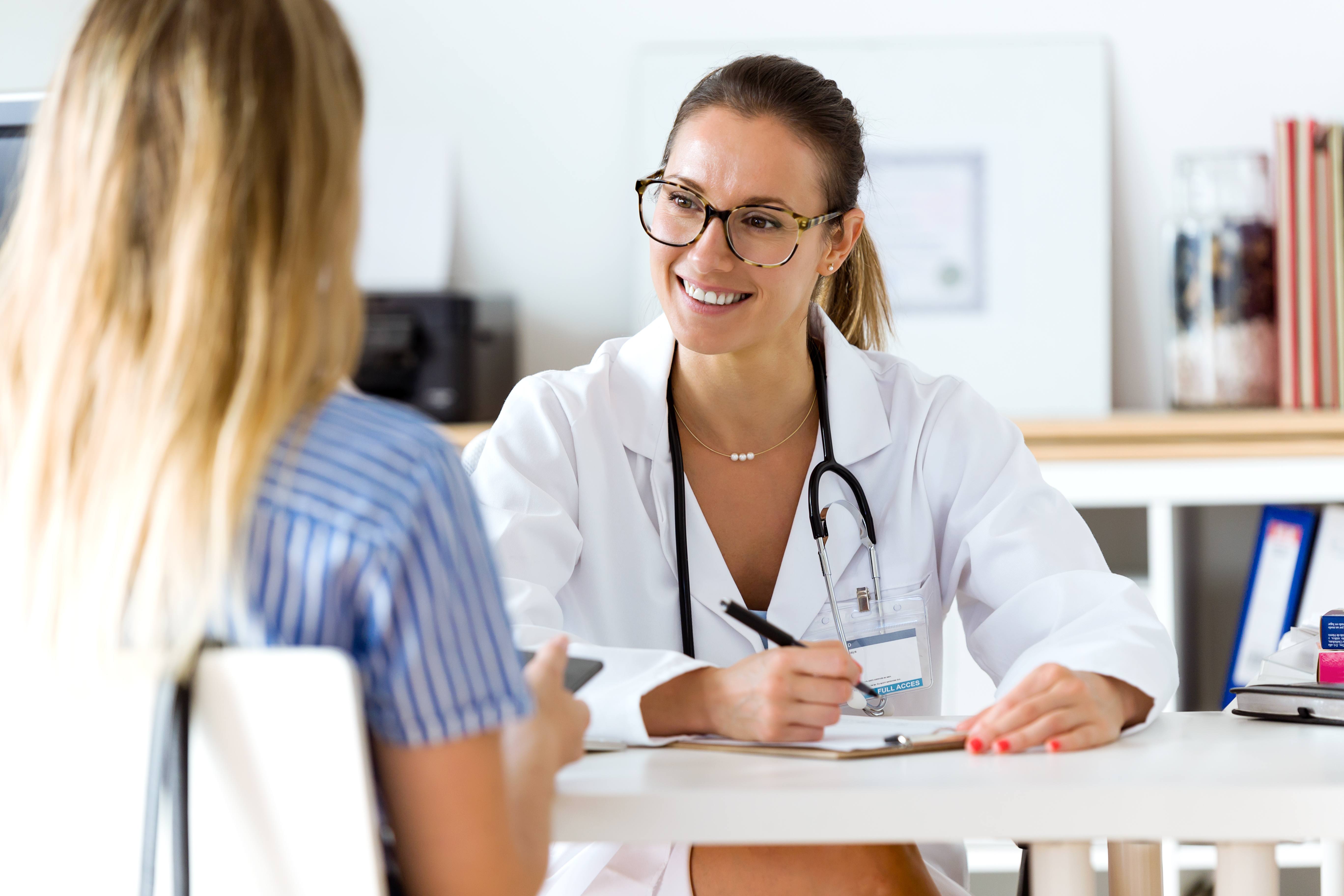 A doctor sitting at a table and discussing healthcare options with her patient.